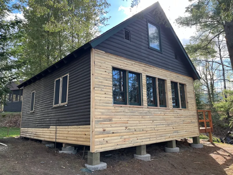 Small wood-sided cabin with a dark gabled roof