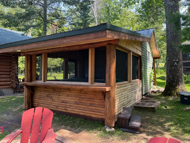 Log cabin porch with screened windows and wood decking