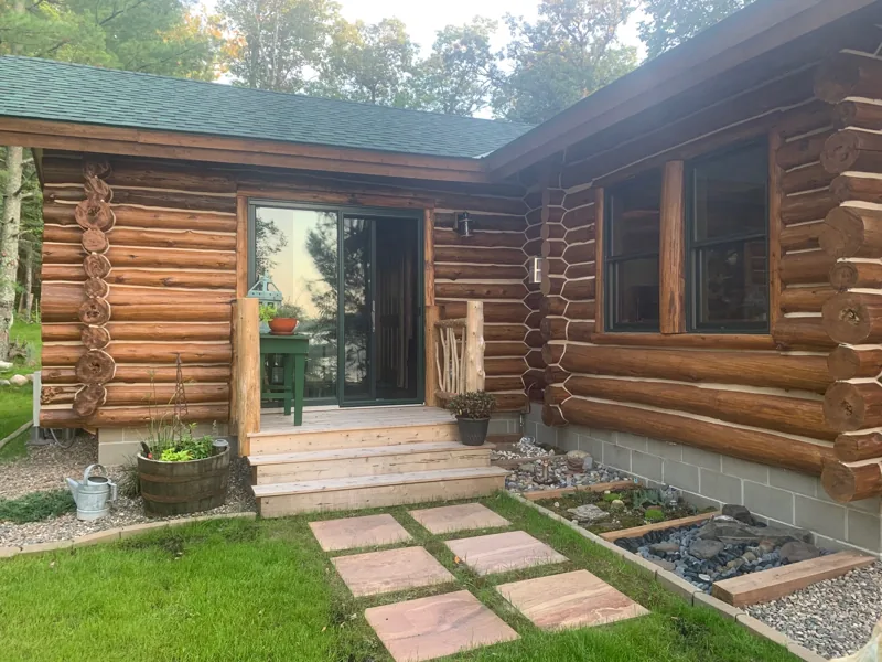 Log cabin entrance with a green roof and landscaped path