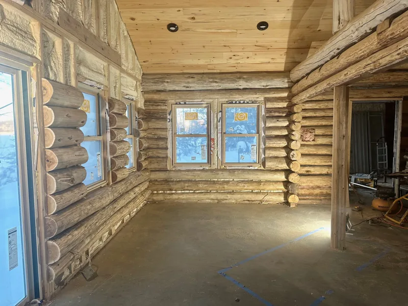Log room with a wood ceiling and blue-trimmed windows