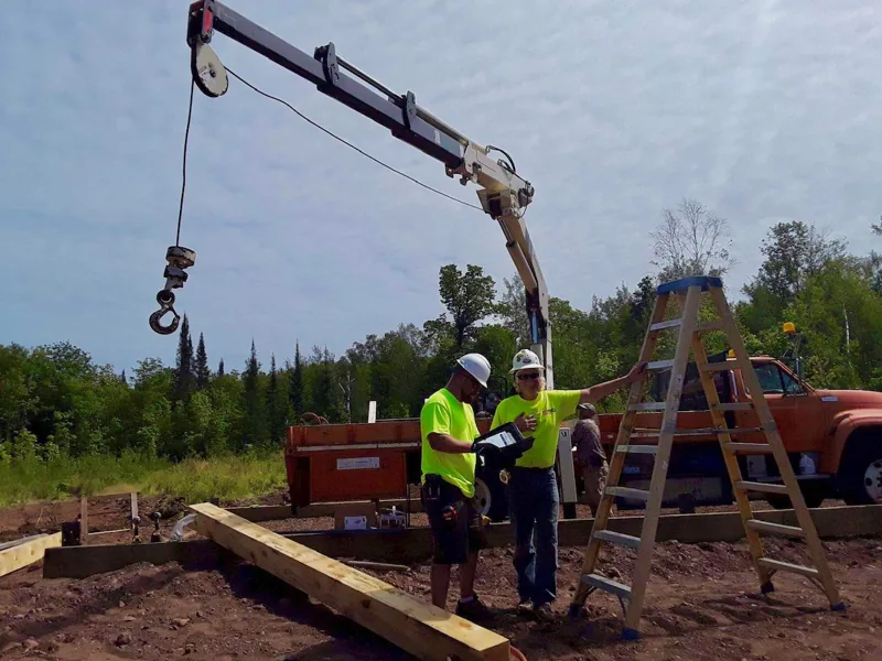 Crane lifting a timber at an outdoor work site
